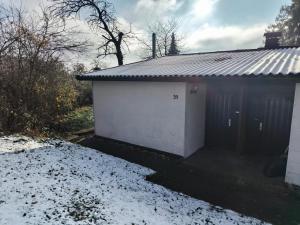 a white garage with snow on the ground next to it at Cozy cottage in Lichtenau