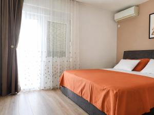 a bedroom with a bed with an orange blanket and a window at Apartment Ivan in Marina +35 photos