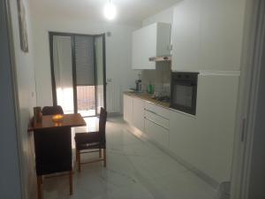 a kitchen with white cabinets and a table and a chair at BEB LA Perla in Sammichele di Bari