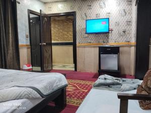 a room with two beds and a flat screen tv at Hotel The Shalimar in Lahore