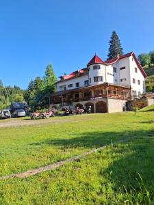 a large building with a grass field in front of it at Vila Apuseni in Arieşeni