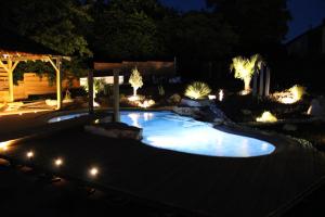 a pool in a yard at night with lights at Tiny House chez Lili in Frémifontaine