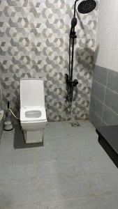 a bathroom with a white toilet and a wall at Gems Palace Hotel Naltar in Jugut