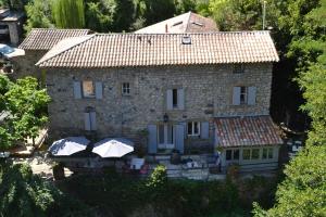 an old stone house with umbrellas in front of it at Maison Sous Le Pont in Meyras