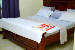 a bed with white sheets and red towels on it at standalone in Fort Portal
