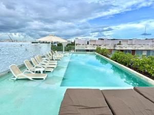a swimming pool with lounge chairs and the water at Anah Suites by Las Flores Vacation Rentals in Playa del Carmen