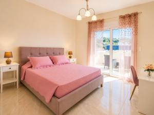 a bedroom with a pink bed and a large window at Ma Maison Rose in Kremasti