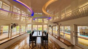 a dining room with a table and chairs and windows at Marari houseboat in Mararikulam