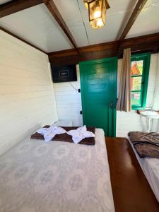two beds in a room with a green door at Linha Nova Glamping in Gramado