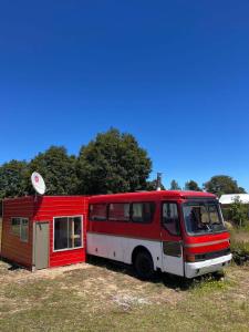 a red and white bus parked next to a tiny house at Cabañas y tinajas in Ancud +5 photos