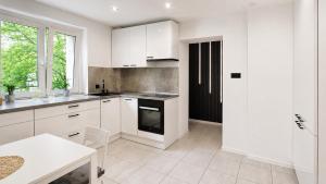 a white kitchen with white cabinets and a window at Bytom Apartament 24H in Bytom