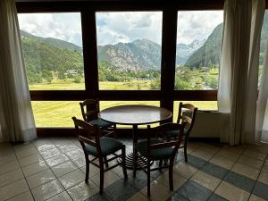 a table and chairs in a room with a large window at Hotel du Foyer Brusson in Brusson