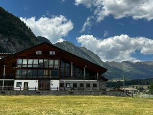 a large building with mountains in the background at Hotel du Foyer Brusson in Brusson