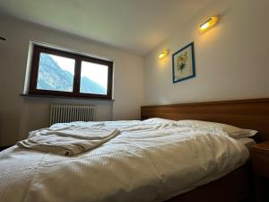 a bedroom with a white bed with a window at Hotel du Foyer Brusson in Brusson +12 photos