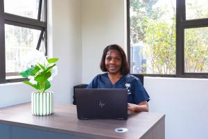 a woman sitting at a desk with a laptop at Ferry Palms Guest Lodge in Arcadia