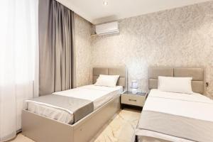 two beds in a room with white walls at Şimal Hotel in Quba