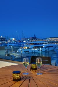 two wine glasses sitting on a wooden table with a view of a harbor at Syranna in Ermoupoli +12 photos