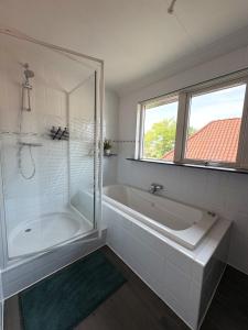 a white bathroom with a tub and a shower at B&B Wetterwille in Opeinde