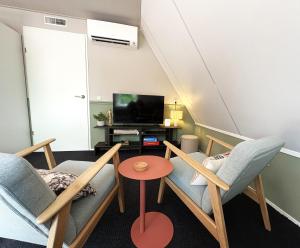 a living room with two chairs and a tv at B&B Wetterwille in Opeinde
