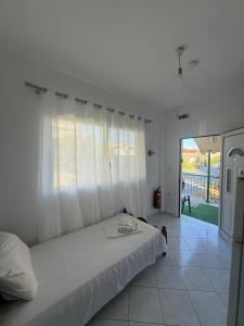 a white bedroom with a bed and a balcony at FLISVOs 70 m από την θάλασσα in Erateini