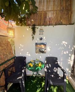 a patio with two chairs and a table with fruit on it at FLISVOs 70 m από την θάλασσα in Erateini