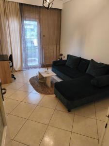 a living room with a black couch and a table at Flat30 - Cosy apartment in Park of Kipseli- Xanthi in Xanthi