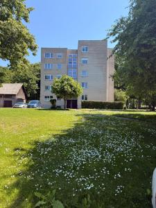a large building with a field of flowers in the grass at Parko apartamentai Kretinga in Kretinga
