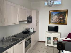 a kitchen with white cabinets and a sink at Smartop Apartment in Forte dei Marmi
