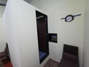 a hallway with a clock on the wall and a chair at Pilankar Guest House in Ratnagiri