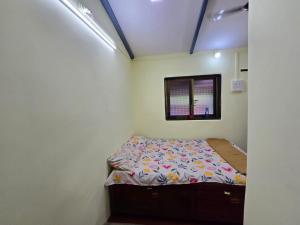 a small bedroom with a bed and a window at Pilankar Guest House in Ratnagiri
