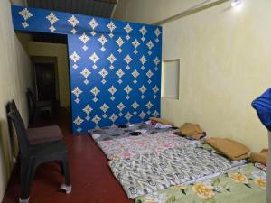 a bedroom with a bed and a chair and a wall at Pilankar Guest House in Ratnagiri