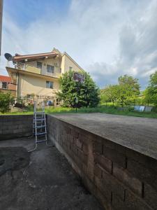a brick wall with a ladder in front of a building at Nin Apartman Free Parking in Kaluđerica