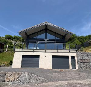 a house with two garage doors and a balcony at Chalet du paradis in La Bresse