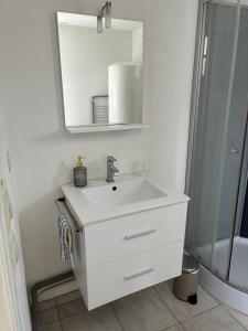 a white bathroom with a sink and a mirror at Maisonnette in Chambon-sur-Voueize
