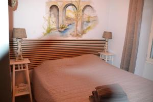 a bedroom with a bed with a painting on the wall at Maison Sous Le Pont in Meyras