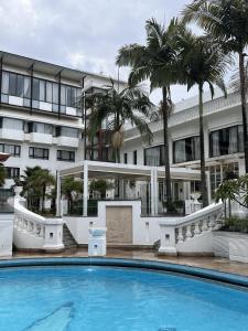 a swimming pool in front of a building with palm trees at Hotel Himalaya Kathmandu - Your Business & Leisure Retreat in Kathmandu