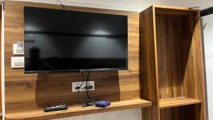 a flat screen tv in a wooden entertainment center at Universal Inn in Chennai