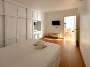a white bedroom with a bed and a television at Link Mansion in Chiang Mai