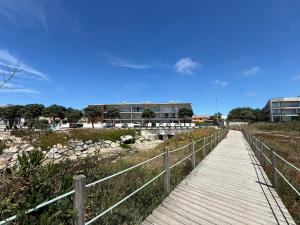 a wooden boardwalk leading to a building on the beach at Sol Poente Praia Apartment in Apúlia