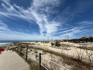 a wooden path to a beach with a blue sky at Sol Poente Praia Apartment in Apúlia +15 photos