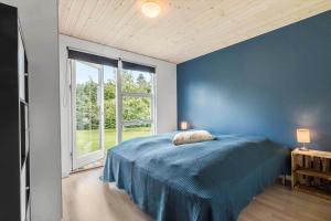 a blue bedroom with a bed and a window at 8843-Glesborg-Lyngtoften-34 in Glesborg