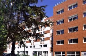 a large brick building with a tree in front of it at Studio lumineux et climatisé avec parking gratuit - Tramway devant la résidence - appartement 114 in Grenoble