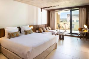 a bedroom with a large bed and a living room at Hôtel Spa & Restaurant - Son de Mar in Porto-Vecchio
