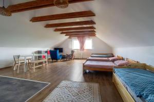 a attic room with beds and a dining room with a table at Apartmán 7J in Hnanice