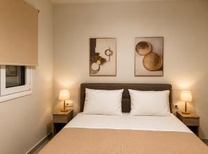a bedroom with a bed with two lamps and pictures on the wall at ΕΝ ΑΛΩ Residences in Kiveri