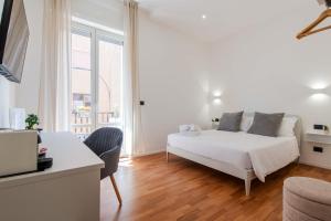 a white bedroom with a bed and a desk and a window at Lumen Boutique Stay in Naples