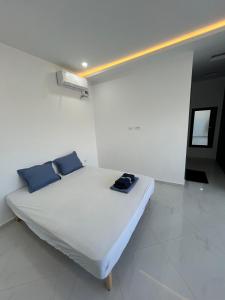 a white room with a bed with blue pillows at Villa blanca in Al Maqārisah +30 photos