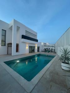 a swimming pool in the backyard of a house at Villa blanca in Al Maqārisah