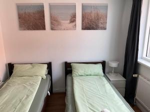two beds in a bedroom with three pictures on the wall at Apartment Altstadt Stralsund in Stralsund