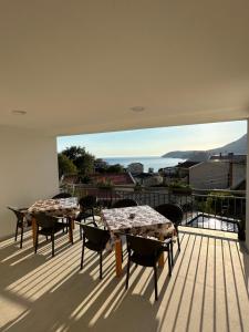two tables and chairs on a balcony with a view at Apartmani Becic in Sutomore